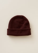 A dark burgundy knit beanie hat with a folded cuff, displayed flat against a light beige background.