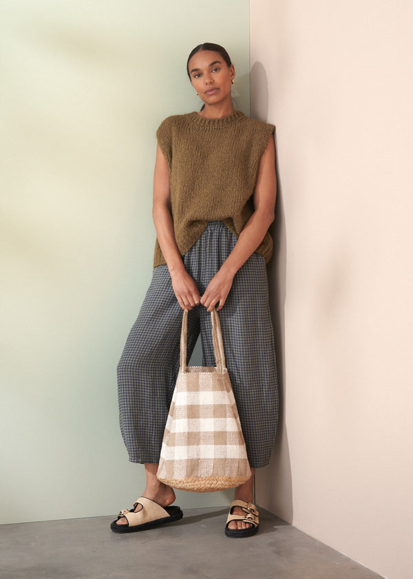 Woman holding a checkered bag against a plain wall