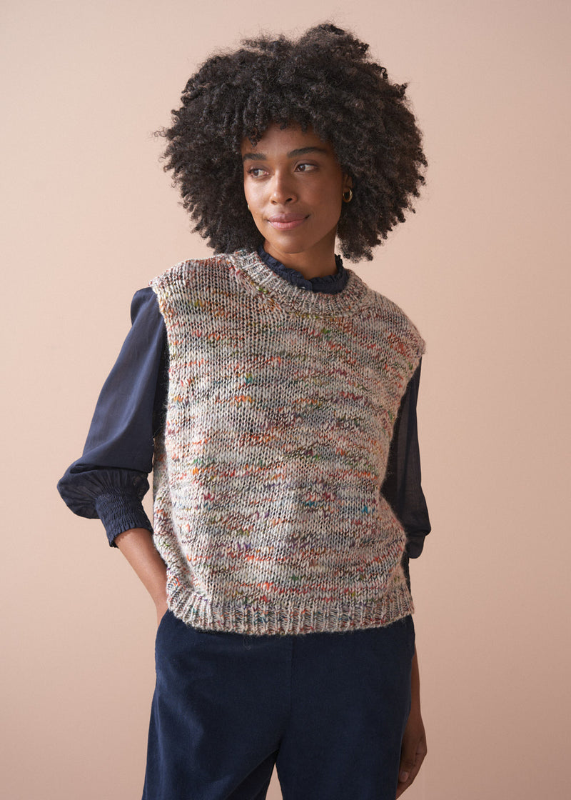 Woman wearing a sleeveless space dye sweater vest against a beige background