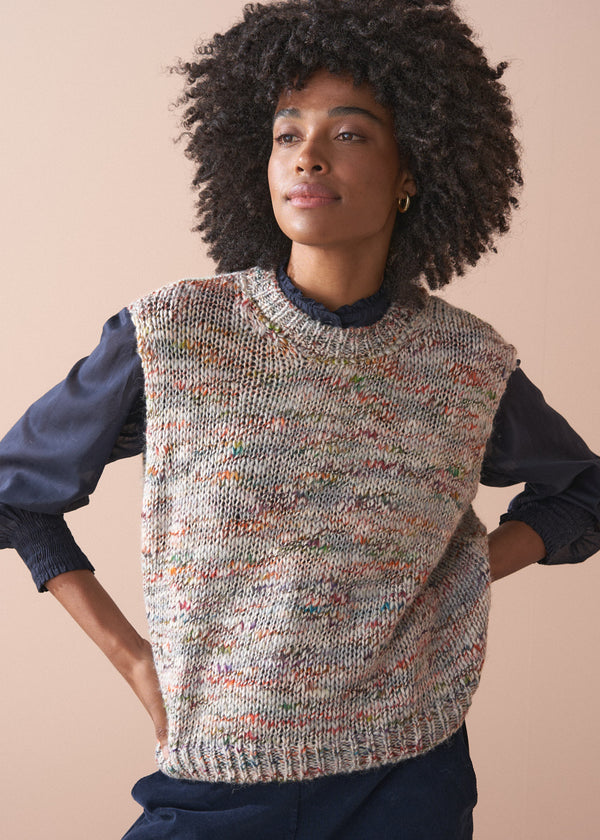Woman wearing a knitted vest with a textured space dye against a beige background