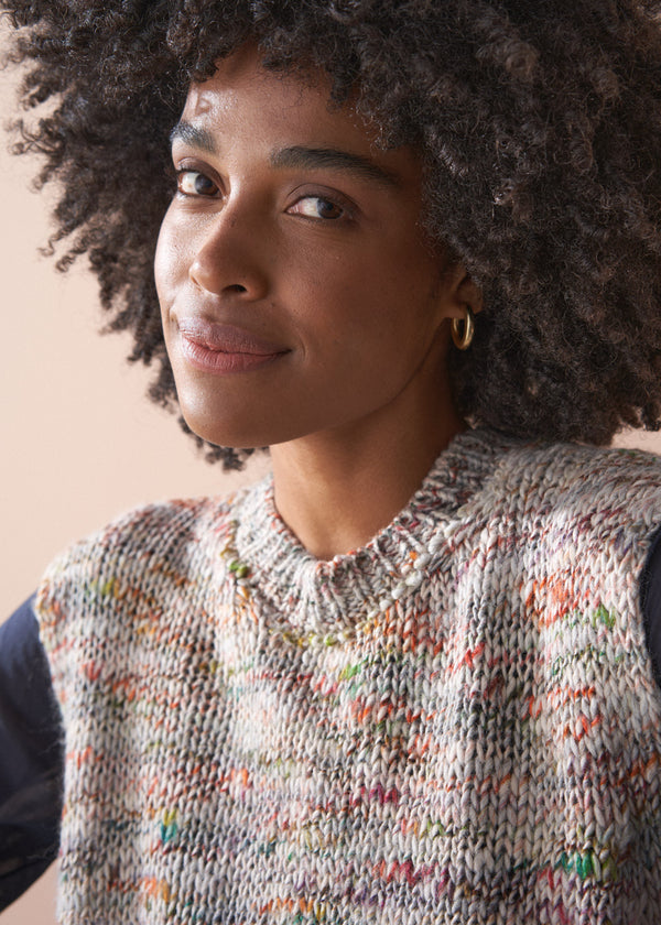 Woman wearing a sleeveless space dye sweater against a neutral background
