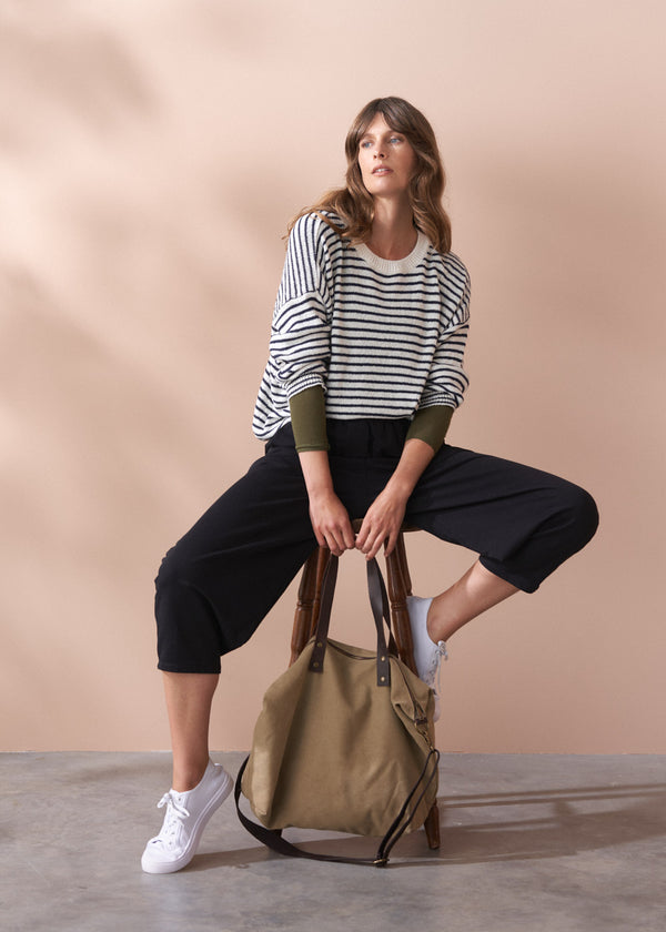Woman holding a beige bag against a beige background