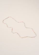 A long beaded necklace with small multicolored beads arranged in an irregular, organic shape, displayed on a plain off-white background.