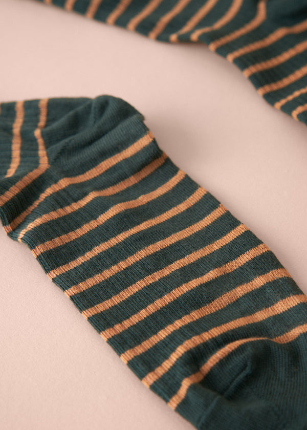 Green and orange striped sock on a light pink background