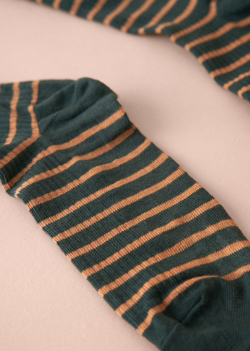 Green and orange striped sock on a light pink background