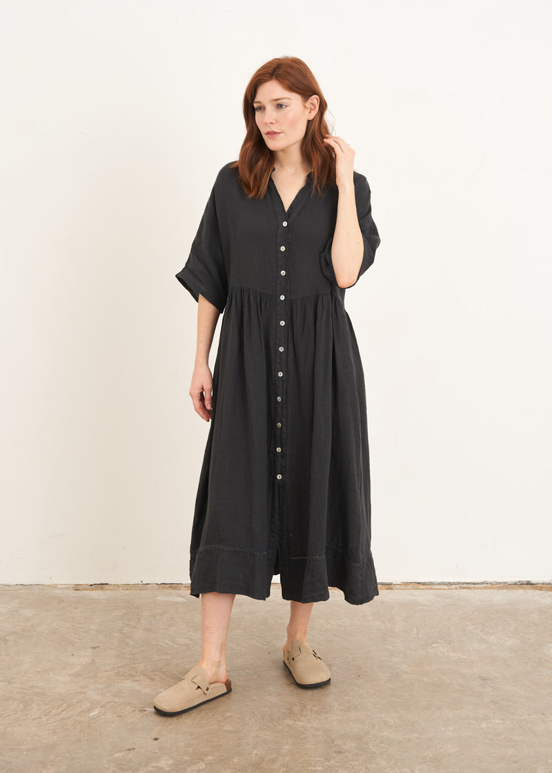 A model wearing a dark grey linen midi shirt dress  with mother of pearl buttons