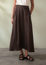 Person wearing a leopard print skirt with a plain background