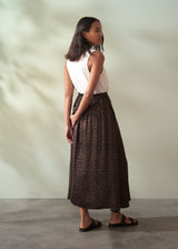 Woman wearing a white top and leopard print skirt against a plain background