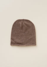 A ribbed knit beanie hat in a muted taupe-brown color, displayed flat against a solid, warm off-white background.