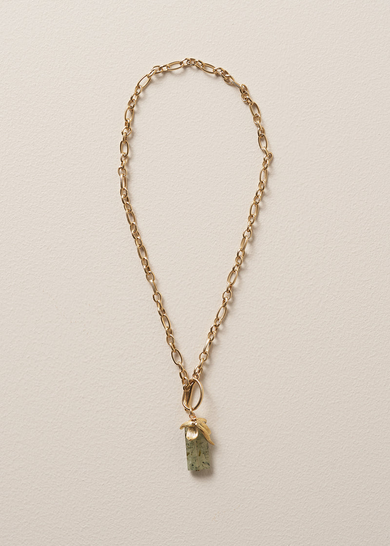Gold chunky chain necklace with a green stone pendant on a beige background