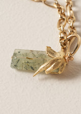 Gold chunky chain necklace with a green stone pendant on a beige background