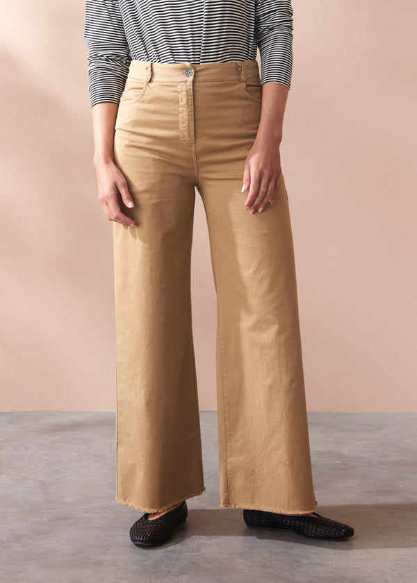 Person wearing beige wide-leg trousers and a striped long sleeve top against a plain background