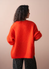 Person wearing a bright red sweater against a beige background