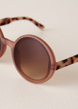 Sunglasses with tortoiseshell arms and brown lenses on a light background