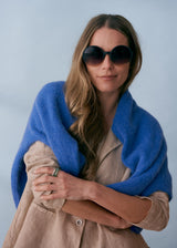 A pair of chunky circular sunglasses with black and pink frames and blue lenses