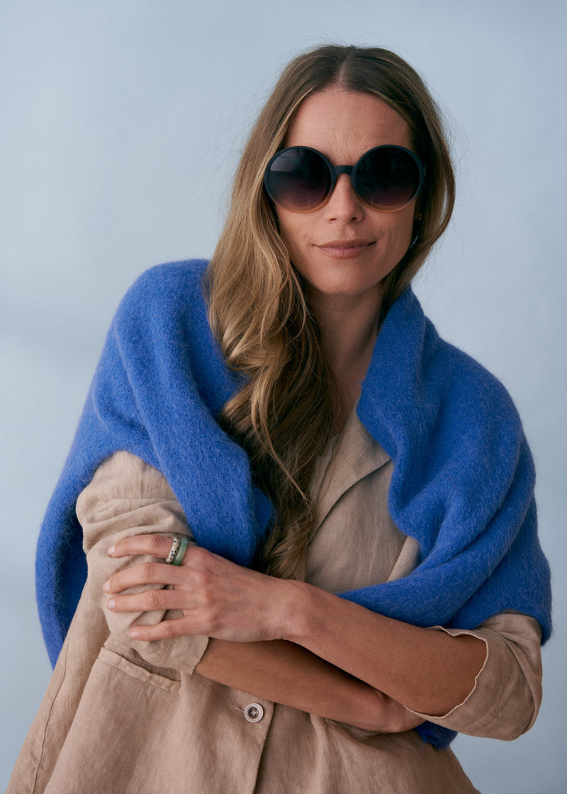 A pair of chunky circular sunglasses with black and pink frames and blue lenses