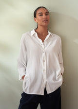 Woman wearing a white button-up shirt against a plain background