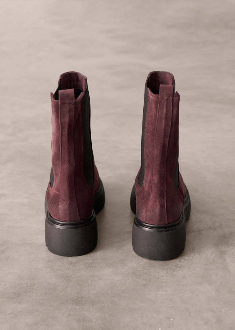Pair of Burgundy suede boots on a beige background