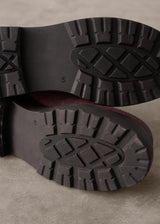 Close-up of black rubber boots with tread pattern on a beige background