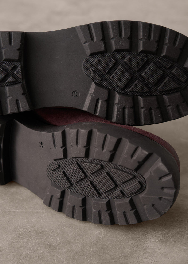 Close-up of black rubber boots with tread pattern on a beige background