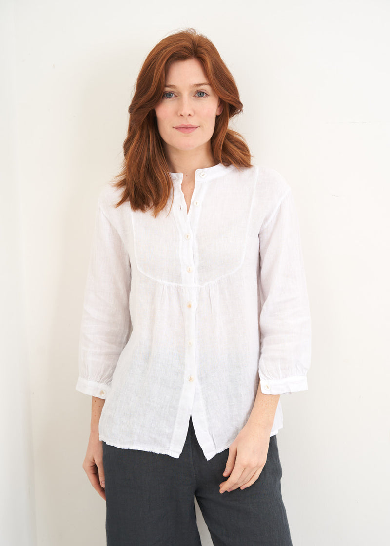 A model wearing a white linen bib shirt with 3/4 sleeves