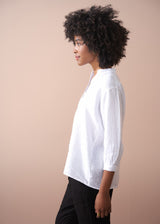 Person wearing a white shirt against a beige background