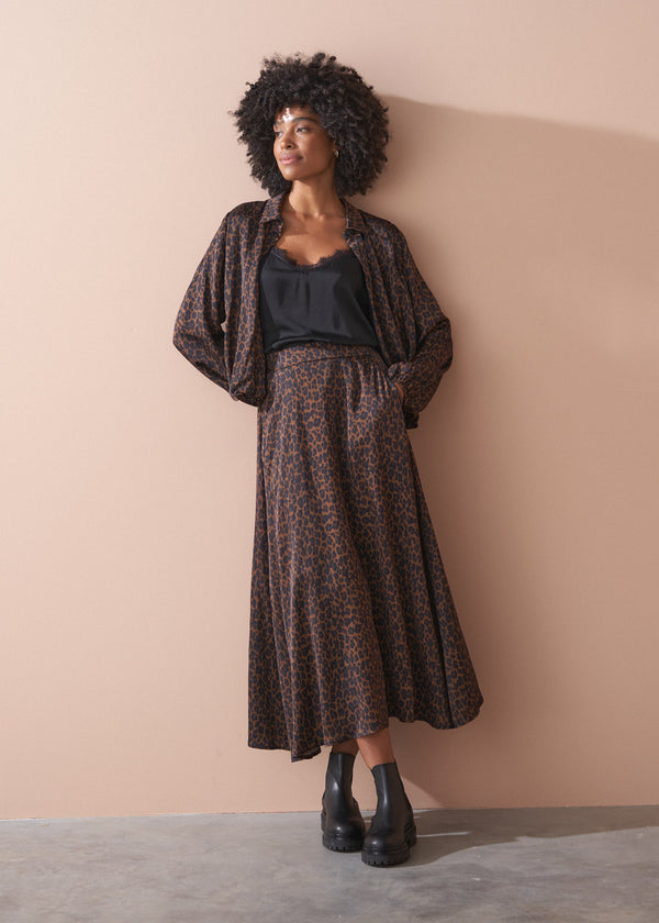 Woman wearing a leopard bubble hem shirt outfit against a beige wall