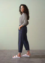 Woman wearing a striped shirt and dark jeans against a plain background