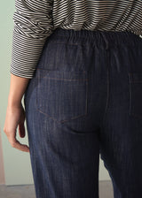 Person wearing dark blue denim jeans with a striped shirt.