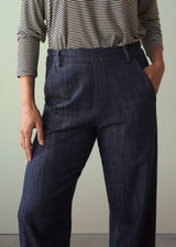 Person wearing a striped shirt and dark blue jeans against a plain background
