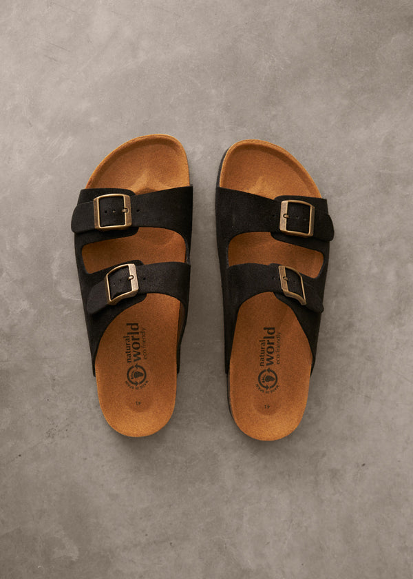 Pair of black sandals with brown soles on a gray surface