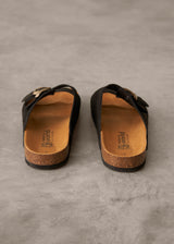 Pair of black sandals with cork soles on a gray surface
