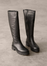 Pair of black knee-high boots on a gray background