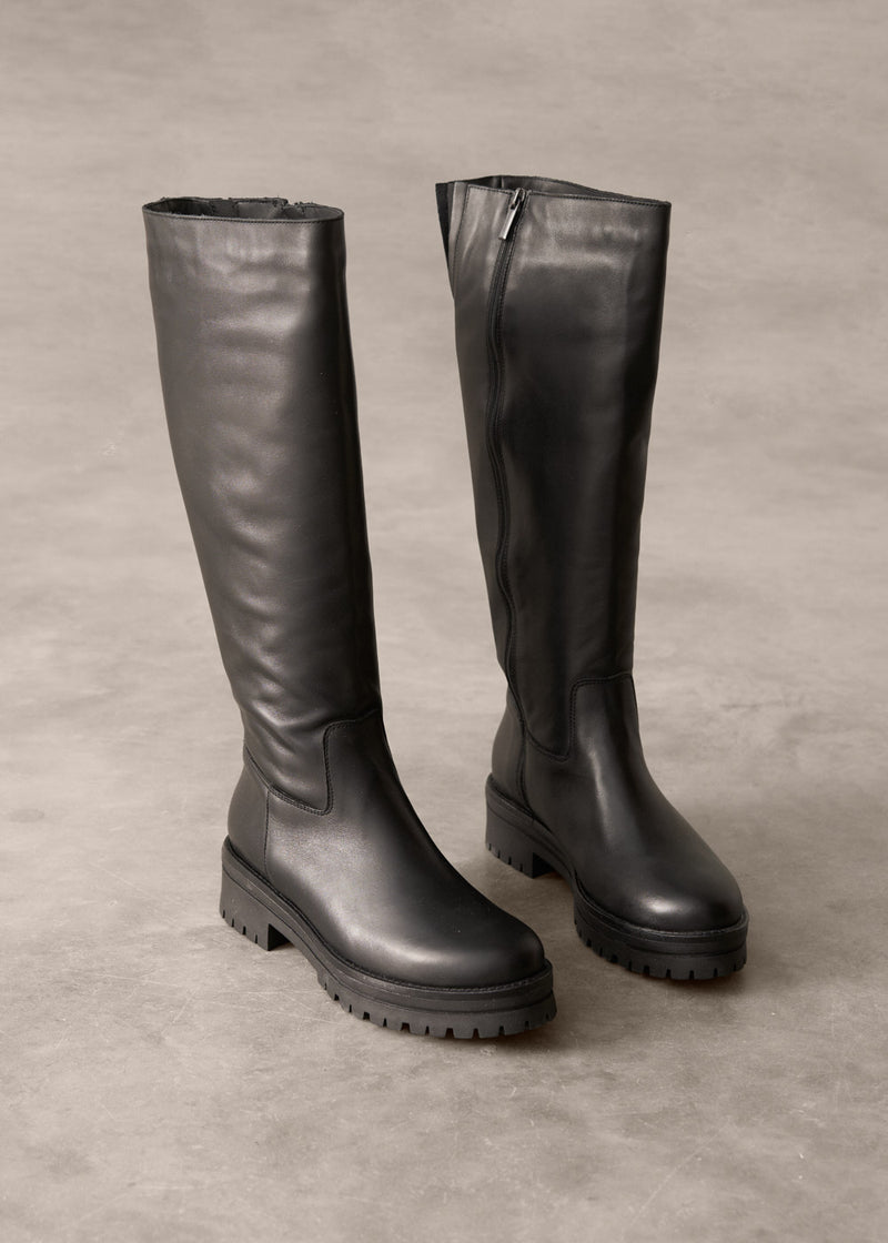 Pair of black knee-high boots on a gray background