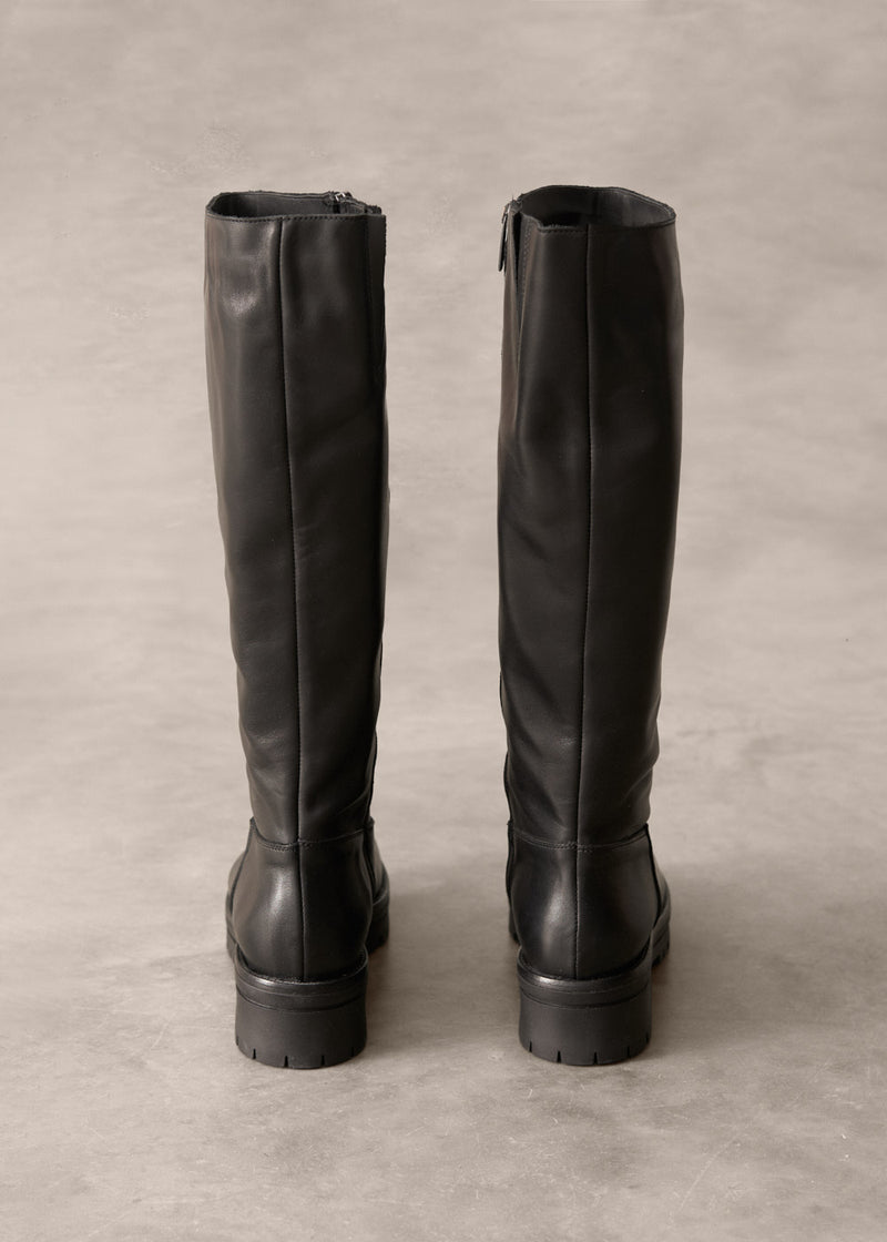 Pair of black knee-high boots on a light gray background