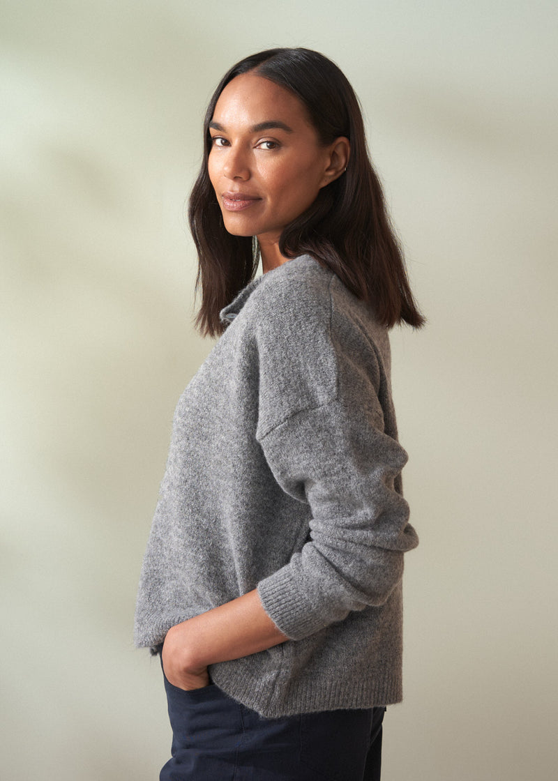 Woman wearing a grey sweater against a plain background