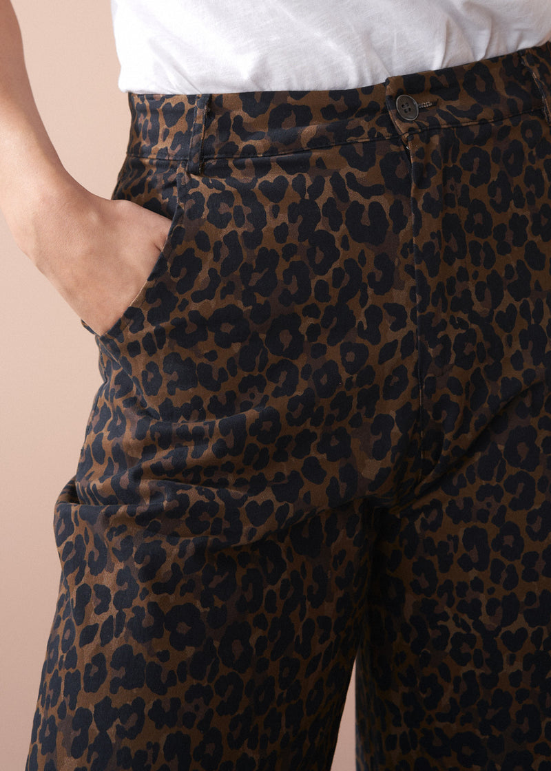 Leopard print pants worn by a person on a beige background