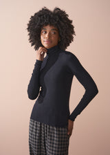 Woman wearing a black turtleneck sweater against a beige background