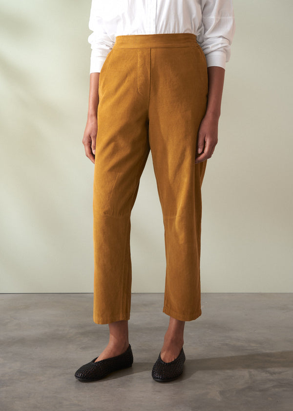 Person wearing mustard yellow corduroy trousers and a white shirt against a neutral background