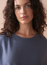 Woman wearing a blue sweater against a beige background