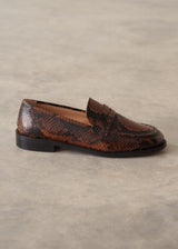 A single brown and black snakeskin-patterned penny loafer shoe, photographed from the side against a neutral gray textured background.