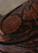 A pair of brown and black snakeskin-patterned penny loafers on a textured gray concrete surface.