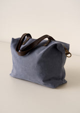 Blue bag with brown leather handles on a beige background