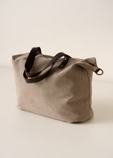 Beige tote bag with brown leather straps on a light beige background