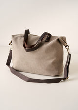 Beige tote bag with brown leather straps on a light beige background