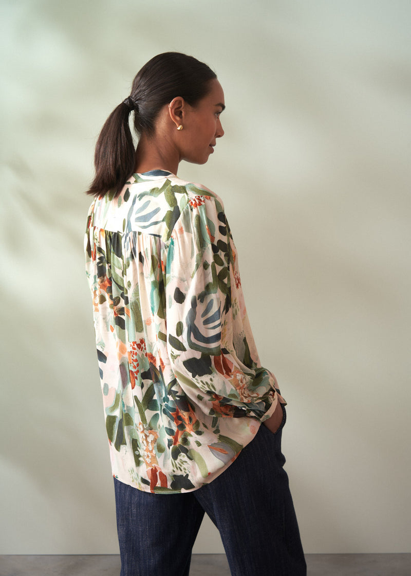 Woman wearing a colorful floral blouse against a plain background