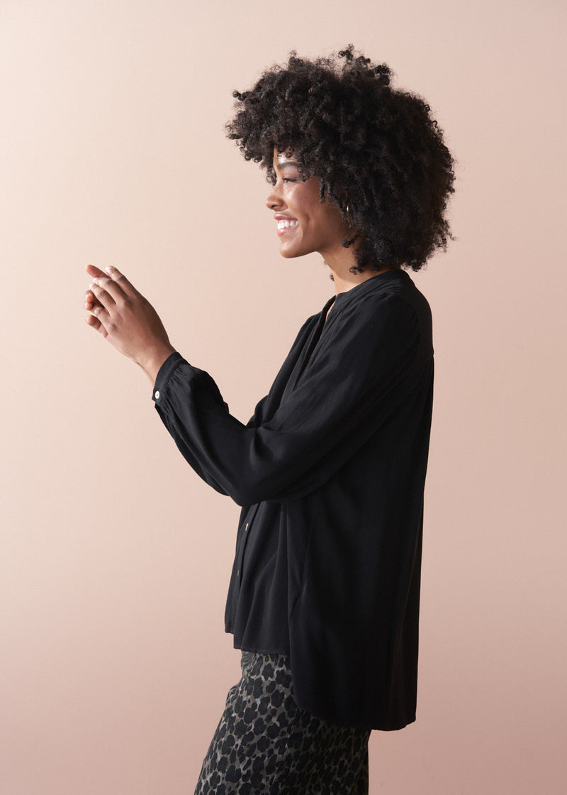 Woman wearing a black top against a beige background
