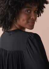 Woman wearing a black blouse against a beige background