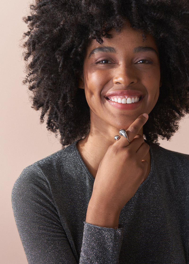 Woman wearing a dark grey shirt against a beige background