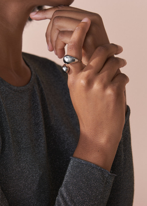 Close-up of a person's hand wearing a ring with a beige background